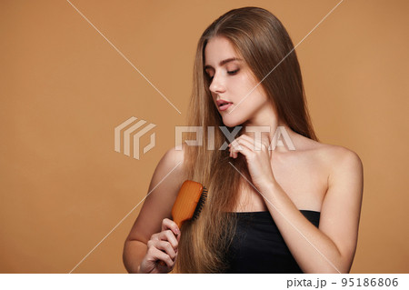 woman combs her long natural hair with wooden brush woman combs her long natural hair with wooden brush 95186806