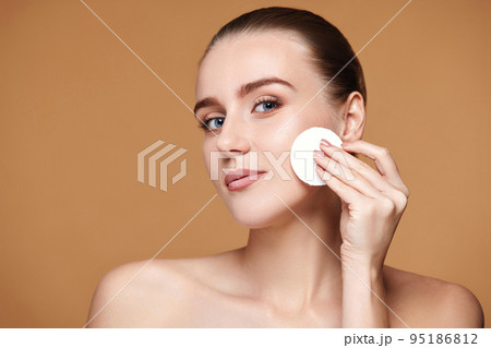 woman holding white cotton pad with micellar water 95186812