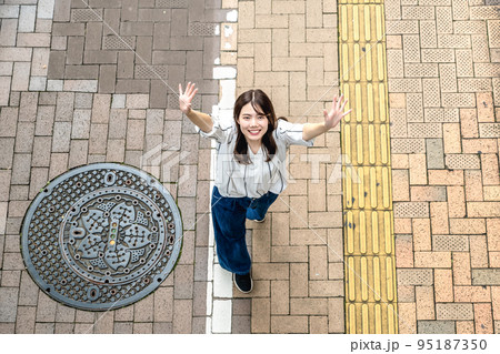 街中を散歩する若い女性　手を振る　俯瞰撮影 95187350