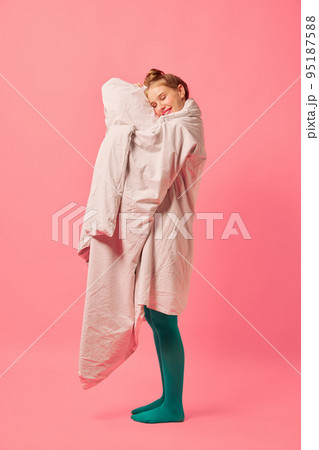 Beautiful young girl wrapped in soft blanket standing isolated over pink background. Comfrort, fashion, art, creativity Beautiful young girl wrapped in soft blanket standing isolated over pink background. Comfrort, fashion, art, creativity 95187588