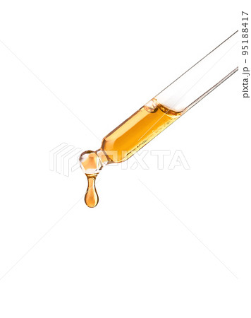 Cosmetic pipette with yellow oily drop on white bg 95188417