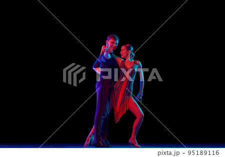 Two dancing people, ballroom dancers in elegance outfits in motion, action over dark background in neon light. Concept of art, music, dance, emotions. Two dancing people, ballroom dancers in elegance outfits in motion, action over dark background in neon light. Concept of art, music, dance, emotions. 95189116