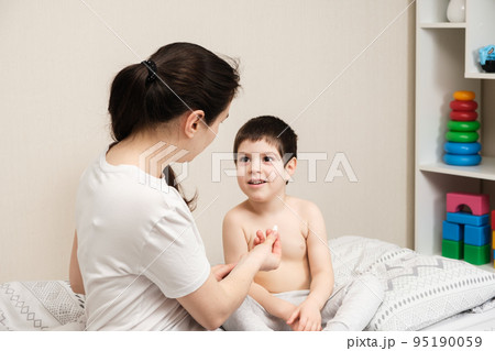 Mom gives a pill to the child, treating the children at home. Childhood diseases, dietary supplements or vitamin D. 95190059