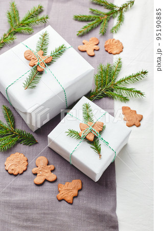 Christmas gifts wrapped in white paper and decorated with spruce sprigs and gingerbread cookies Christmas gifts wrapped in white paper and decorated with spruce sprigs and gingerbread cookies 95190885