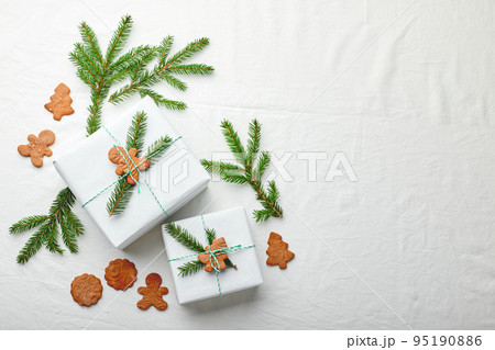 Christmas gifts wrapped in white paper and decorated with spruce sprigs and gingerbread cookies Christmas gifts wrapped in white paper and decorated with spruce sprigs and gingerbread cookies 95190886