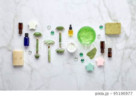 Cosmetic skin care products, jade stone face massager, creams, gel and oil. Roller massage of the face. Flat lay, top view Cosmetic skin care products, jade stone face massager, creams, gel and oil. Roller massage of the face. Flat lay, top view 95190977