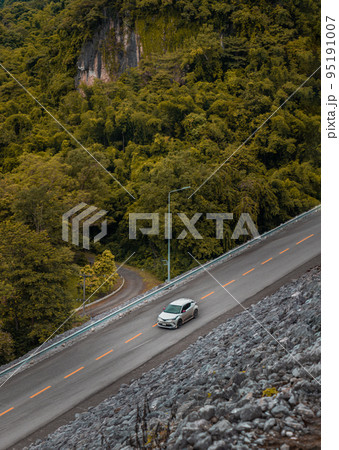 Aerial view of White car drive along a beautiful mountain asphalt road in the autumn season. 95191007