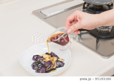 【茄子の揚げびたしを作る　炒めた茄子に麵つゆを入れる】 95193160