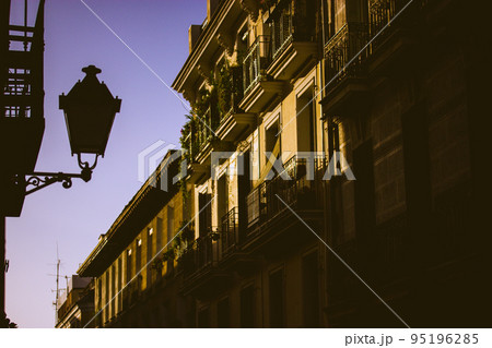 Beautiful photo of an old European street, houses facades, balconies, victorian vintage lantern against evening sky. Postcard from a trip, travel to Spain, Madrid. Sunset in town. Twilight cityscape. 95196285