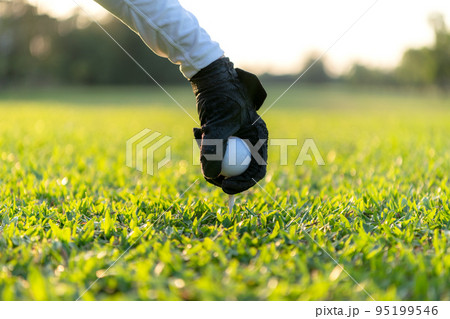 Close up hand asian sporty woman putting golf ball on tee with club in golf course on evening on time Close up hand asian sporty woman putting golf ball on tee with club in golf course on evening on time 95199546