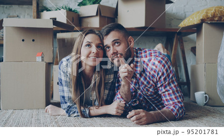 Happy couple is lying on floor in new house talking and smiling. Housing and relationship concept. 95201781