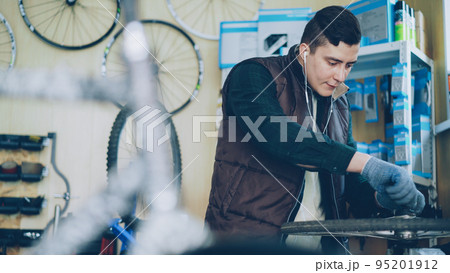 Concentrated repairman in earphones is disassembling mechanism to repair it. People, maintenance and vehicle concept. 95201912
