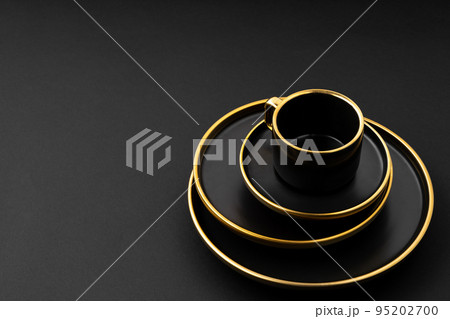 A set of black and golden ceramic plates and cup on a black background 95202700