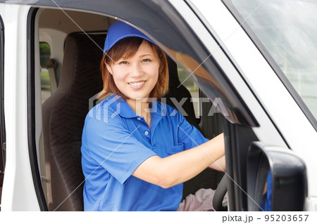 軽トラックを運転する青いキャップとポロシャツを着た笑顔の女性、軽貨物ドライバーとして開業する主婦イメ 95203657