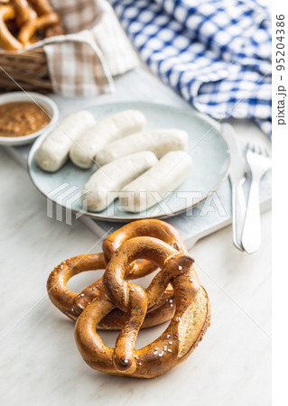 Traditional Bavarian white sausages on plate and pretzes. 95204386