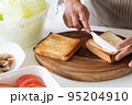 サンドイッチ用の焼き立てのパンにバターを塗る人 95204910