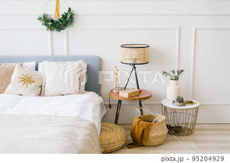 Cozy bedroom with a bed and a Christmas wreath, bedside table Cozy bedroom with a bed and a Christmas wreath, bedside table 95204929
