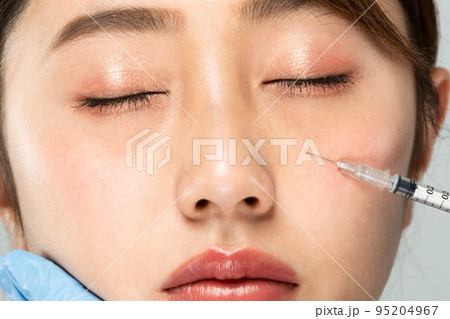 女性の下まぶたに注射器をあてている 95204967