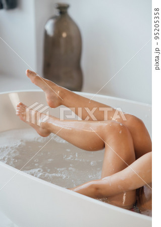 Cropped view of young woman lying in foamy bath Cropped view of young woman lying in foamy bath 95205358