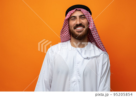 Portrait of young smiling Arab man on orange background 95205854