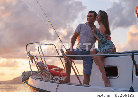 Beautiful couple looking at sunset from the yacht Beautiful couple looking at sunset from the yacht 95206135