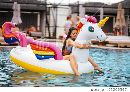 Woman on inflatable unicorn toy mattress float in pool. Woman on inflatable unicorn toy mattress float in pool. 95206547