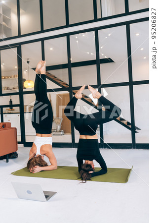 Two young woman working out indoors, doing yoga exercise on mat 95206827