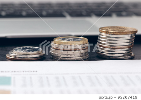 pile of money coins with graph paper on wood table, concept in account, finance and growth of business pile of money coins with graph paper on wood table, concept in account, finance and growth of business 95207419