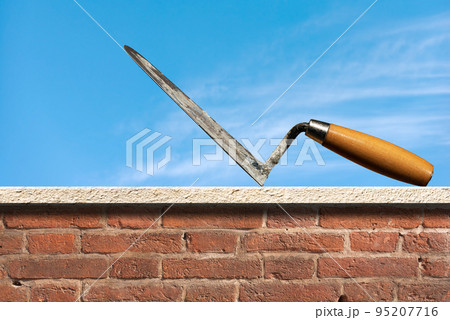Dirty Concrete Trowel with Wooden Handle Above a Brick Wall Dirty Concrete Trowel with Wooden Handle Above a Brick Wall 95207716