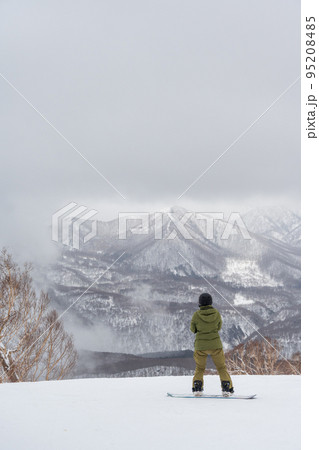 雪が舞う天気が幻想的な雰囲気のスキー場とスノーボーダー 95208485
