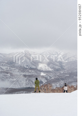 雪が舞う天気が幻想的な雰囲気のスキー場とスノーボーダー 95208487