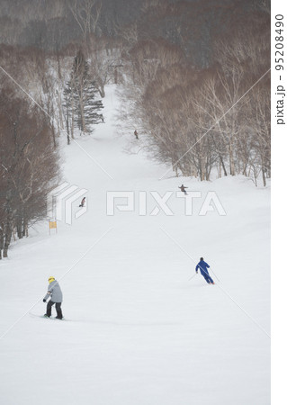 雪が舞う天気が幻想的な雰囲気のスキー場とスキーヤー 95208490