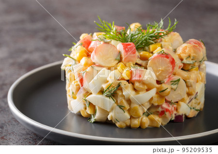 Crab salad with boiled eggs, onion and corn with mayonnaise dressing close-up in a plate. horizontal 95209535