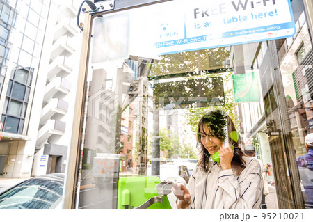 携帯電話の通信障害で公衆電話を使う若い女性 95210021