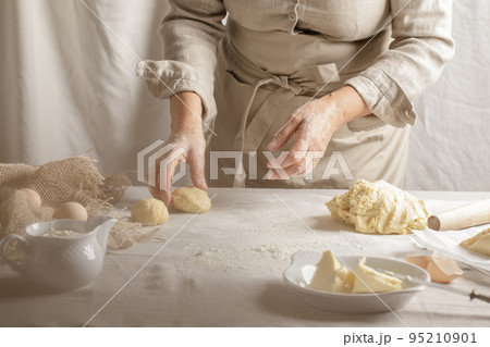 Womens hands, flour and dough. A woman is preparing a dough for home baking. Concept of home cooking with organic and natural ingredients. Zero waste concept 95210901