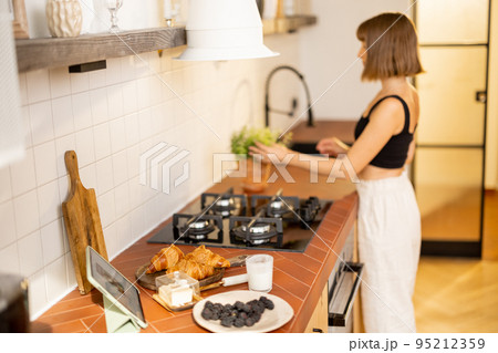 Woman makes a breakfast on kitchen at home 95212359