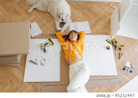 Woman rests with her cute dog, while making repairing at new apartment, 95212447