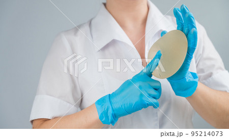 A plastic surgeon shows a breast silicone implant. 95214073