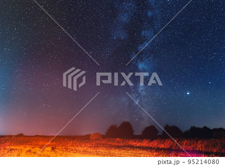 Natural Real Night Sky Stars With Milky Way Over Field Meadow With Rolls Of Straw In Fields After Harvest. Agricultural Colorful Background Copy Space Natural Real Night Sky Stars With Milky Way Over Field Meadow With Rolls Of Straw In Fields After Harvest. Agricultural Colorful Background Copy Space 95214080