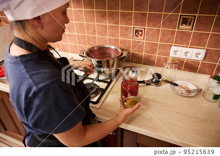 Selective focus. Canning tomatoes for the winter. Canned food. Housewife making preserved from homegrown organic vegetables in the home kitchen 95215639