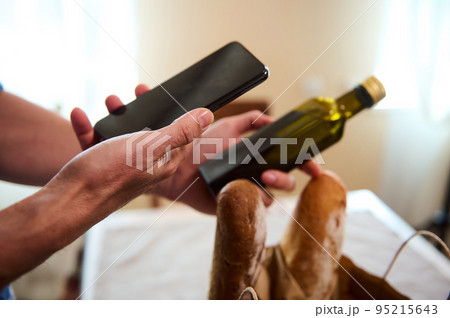 Scanning QR code with smartphone. Close-up man checks the nutrients of olive oil on a smartphone by scanning a barcode, using the application on his mobile phone. Healthy purchasing. Food delivery Scanning QR code with smartphone. Close-up man checks the nutrients of olive oil on a smartphone by scanning a barcode, using the application on his mobile phone. Healthy purchasing. Food delivery 95215643