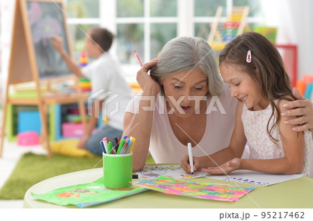 Cute little girl drawing with her grandmother Cute little girl drawing with her grandmother 95217462