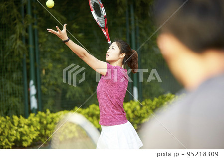 young female asian tennis player working with coach on serving young female asian tennis player working with coach on serving 95218309