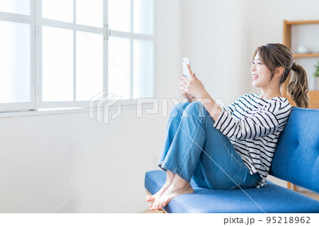 リビングでスマホを操作する若い女性 95218962