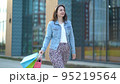 Joyful satisfied woman goes after shopping. A young girl holds bags of different colors in her hands 95219564