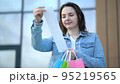 Young woman looks at the prices of goods on a cash receipt after shopping in a mall 95219565