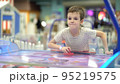 A boy of seven years old enjoys playing air hockey in the playground for entertainment 95219575