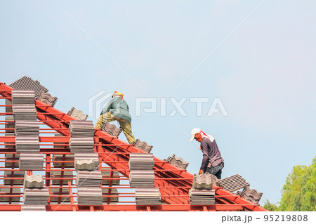 Construction roofer installing roof tiles at house building site Construction roofer installing roof tiles at house building site 95219808
