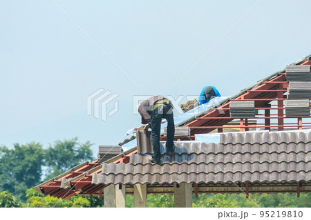 Construction roofer installing roof tiles at house building site Construction roofer installing roof tiles at house building site 95219810