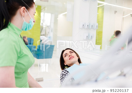 Dental clinic patient is lying in a chair and talking to a doctor. Dental clinic patient is lying in a chair and talking to a doctor. 95220137